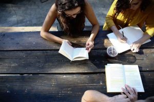 Des jeunes assis autour d'une table sont en train de lire et d'écrire. Communauté d'écriture Scéal studio, plateforme de scénarisation et d'écriture de livres
