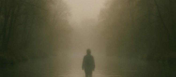 Une rivière recouverte de brume, le matin. Un personnage fantomatique semble marcher au milieu de l'eau. Scéal studio plateforme d'écriture créative.