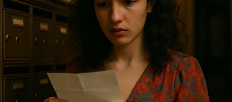 Une jeune femme lit une lettre avec inquiétude à côté de sa boite aux lettres. Scéal studio, plateforme d'écriture créative.